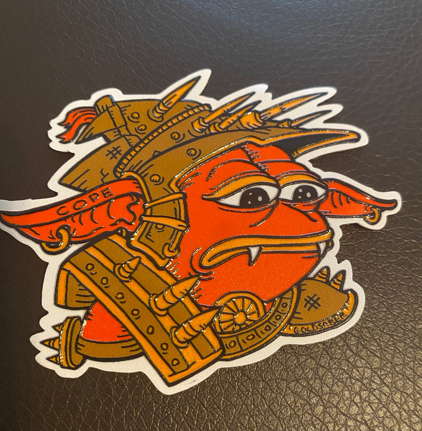 TopDeck.gg Sad Rograkh embossed sticker featuring a red goblin character in spiked armor with a sad expression, illustrated by Tim Taranto (@Goldsabertooth).